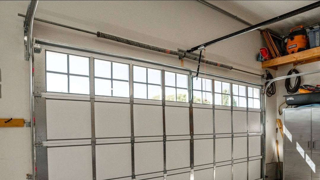 Interior view of a garage door with windows, torsion spring and opener rail installed