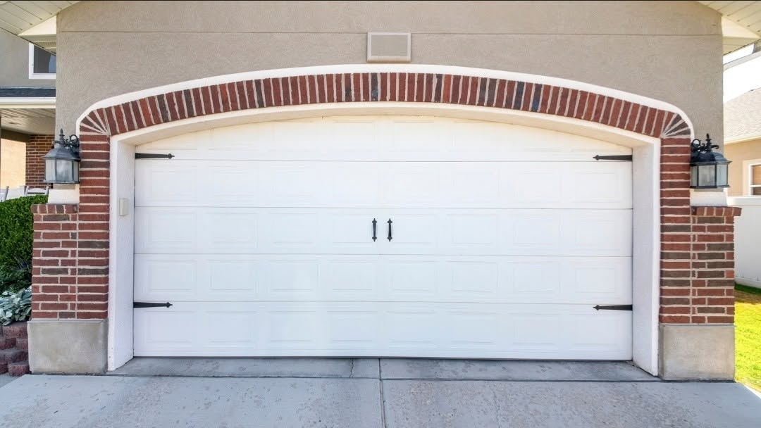 White carriage-style garage door installed on a brick and stucco home