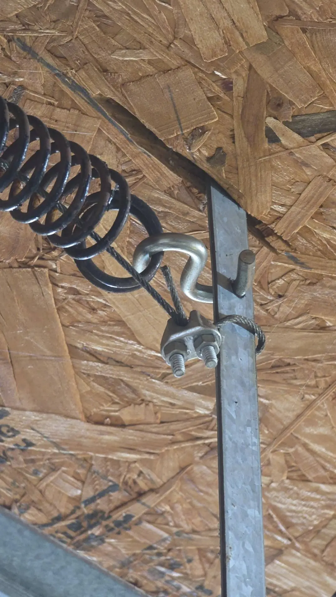 Close-up of a garage door extension spring, cable and safety clamp hardware